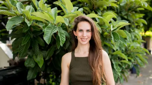 Hayley Quinn standing on the sidewalk posing by a tree